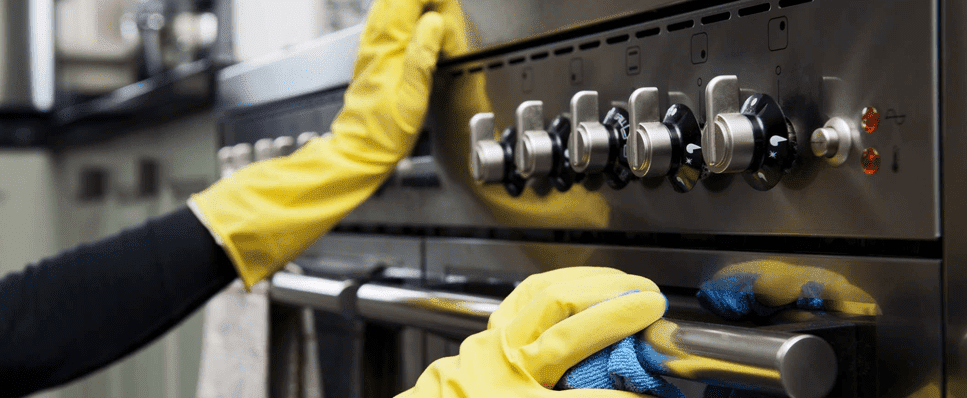 Cleaner wiping the front of an oven